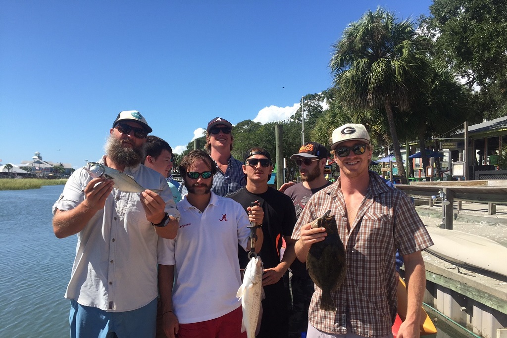 men pose for camera holding fish they caught