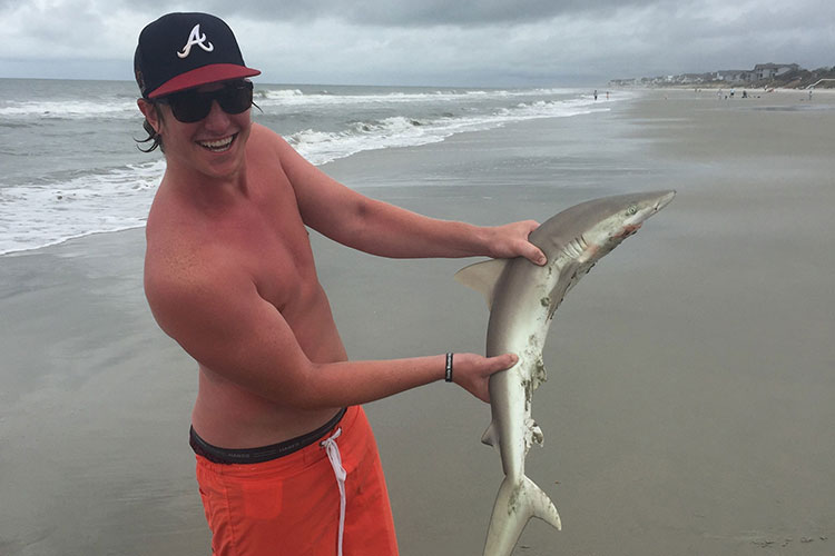 man posing with caught shark