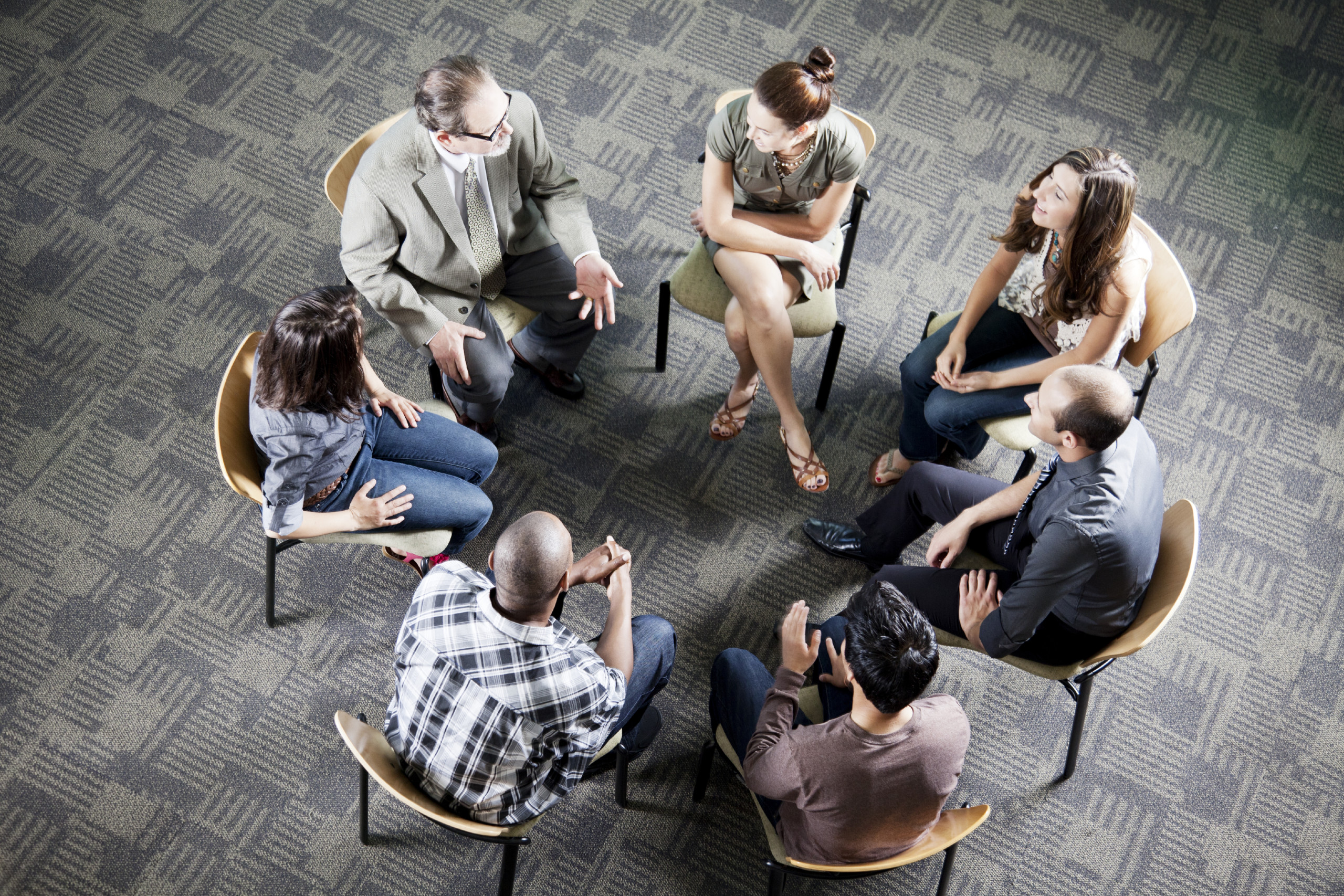 group of young adults and teacher sitting in a circle