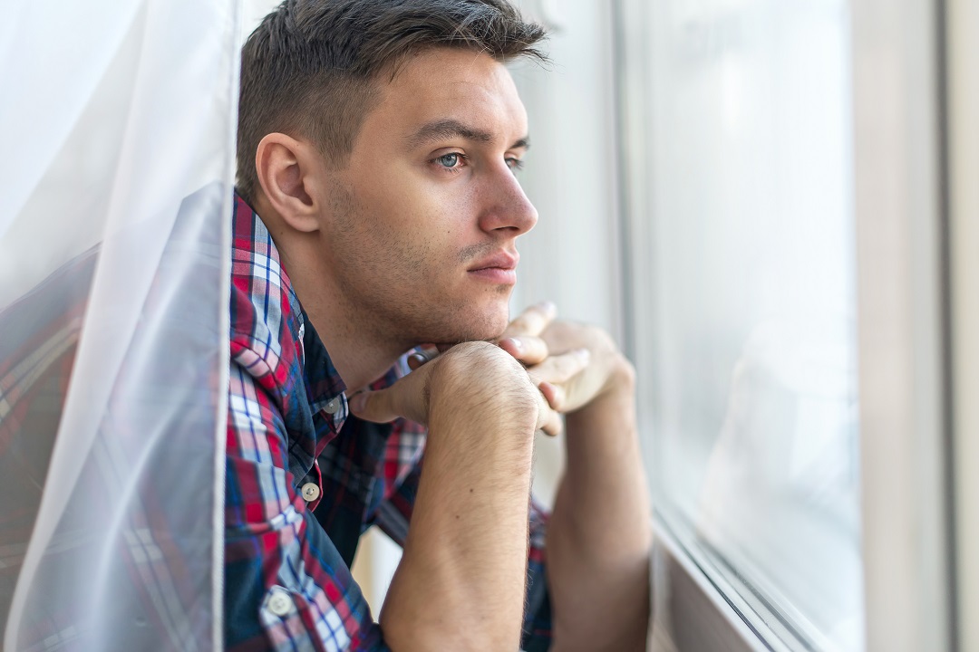 man staring out of window