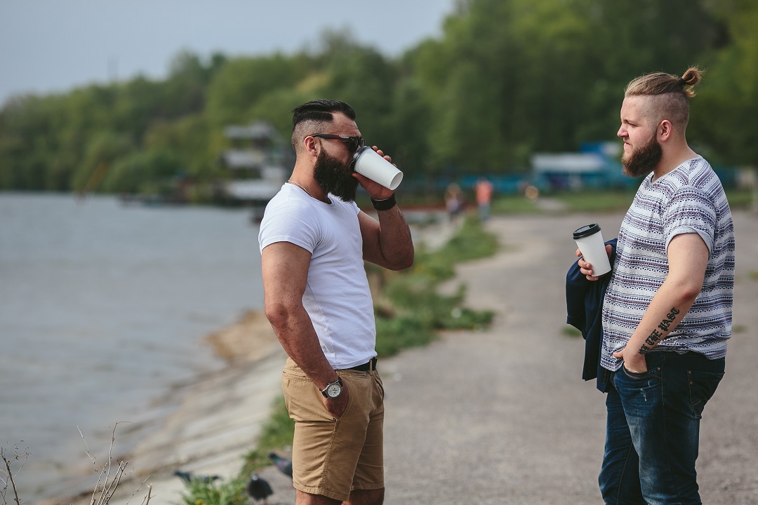 two men chat outside over coffee