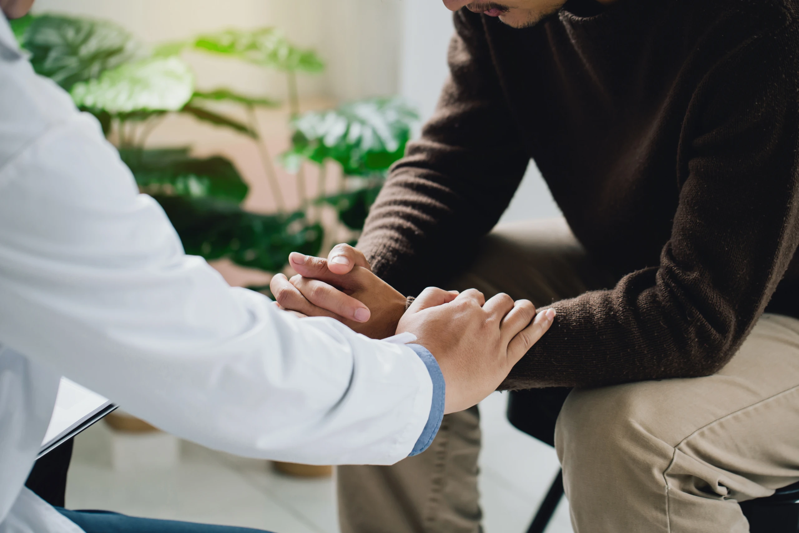 Psychiatrist or professional psychologist holding touching hands patient and comforts an anxious depression patient for medical treatment in diagnostic room, Medical treatment and health care concept.